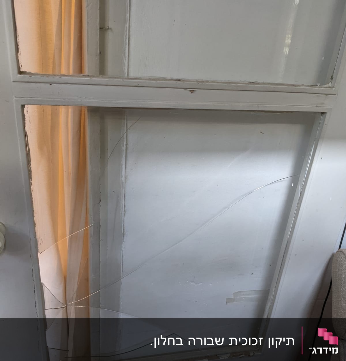 חלון זכוכית שבור עם סדקים גדולים במסגרת עץ